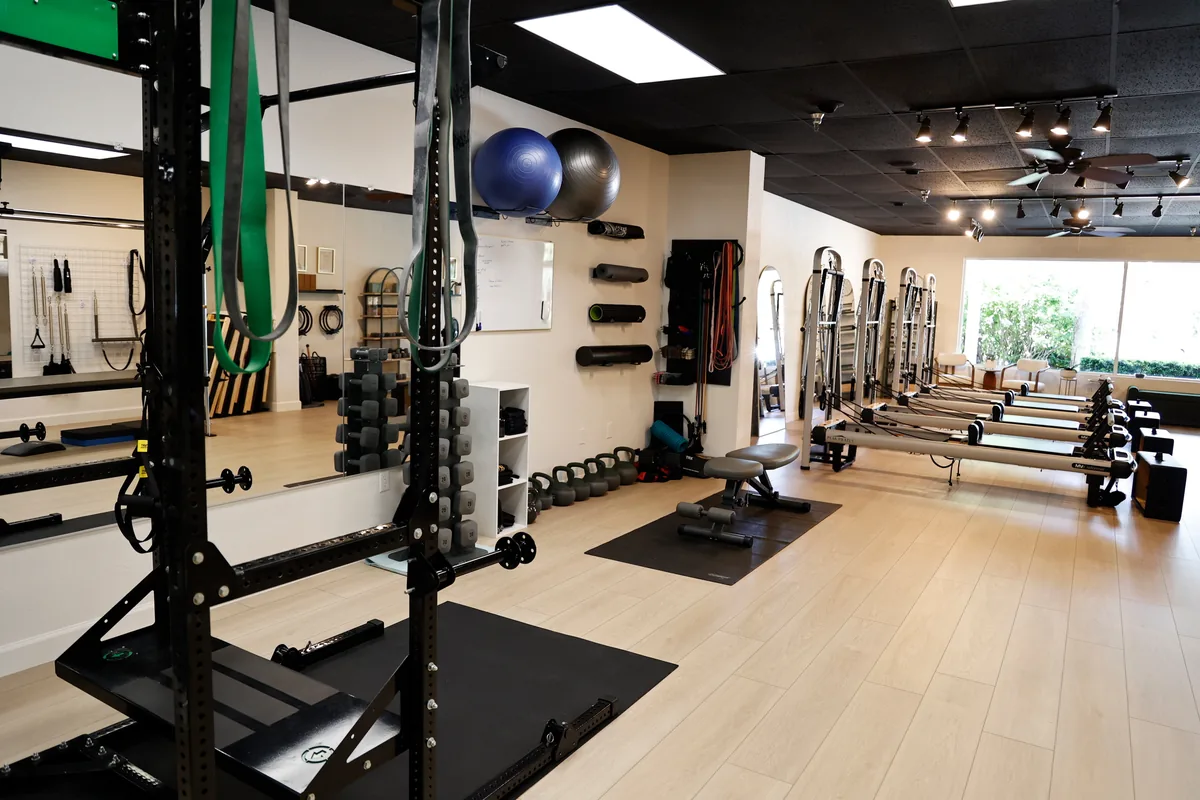 The strength training area at Paradise Pilates with a rack, free weights, and turf
